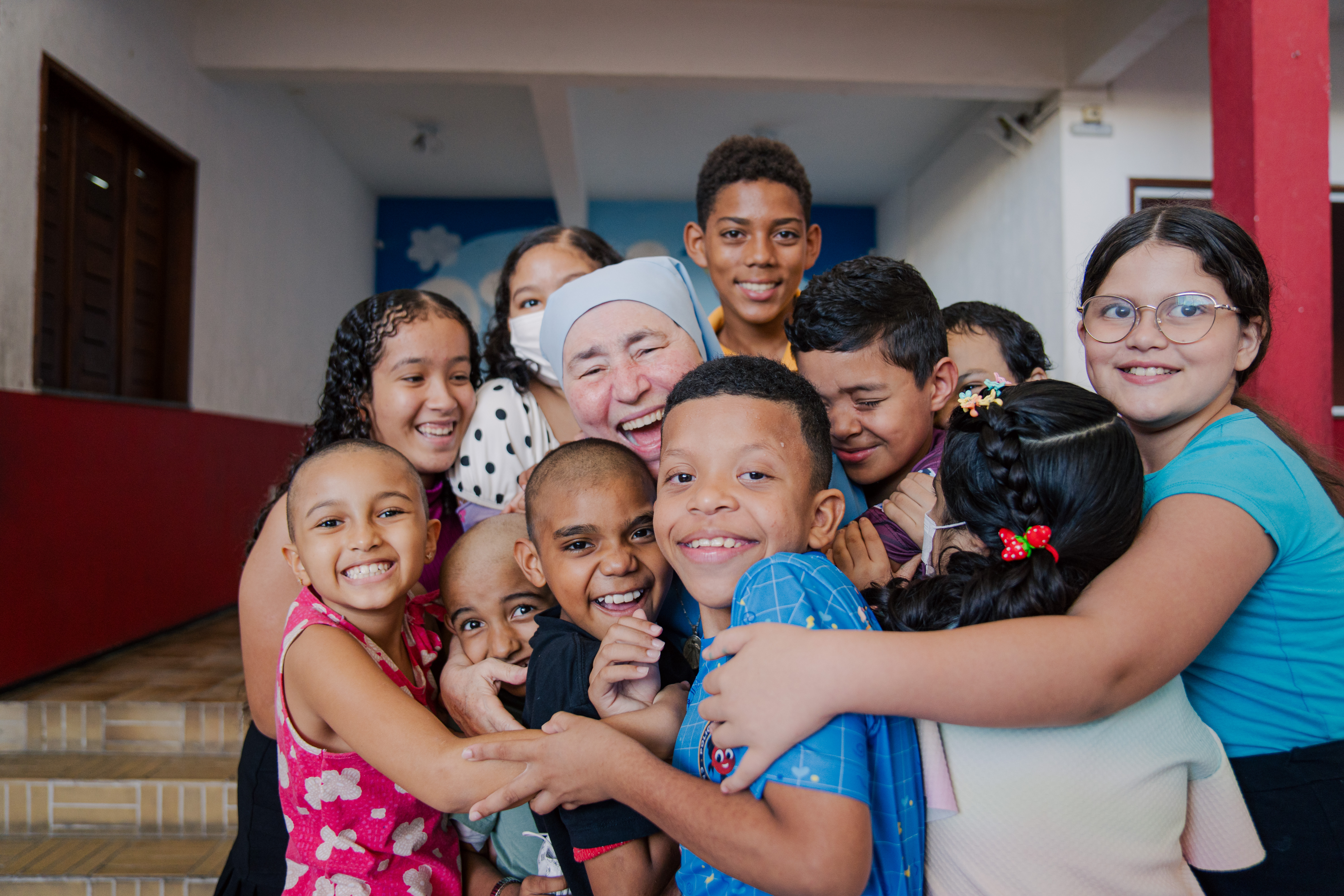 Irmã Conceição abraçada por várias crianças